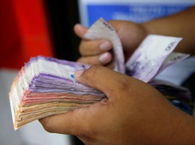 Man counts wad of Philippine Peso bills in Makati