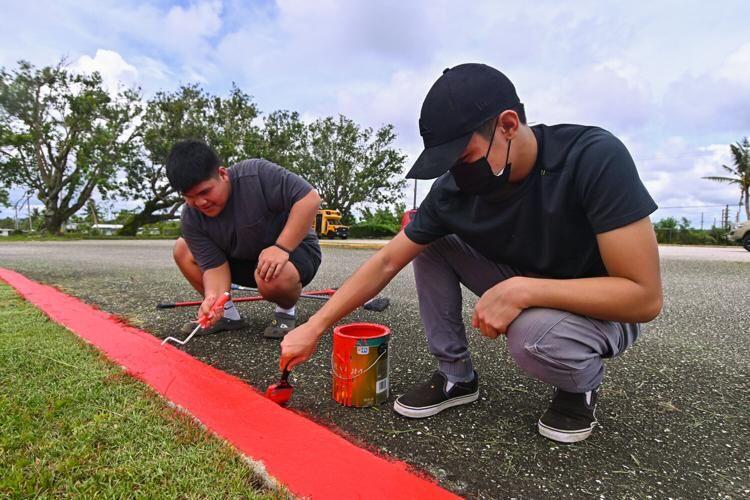 Summer interns Richard Seidler, 16, and Aron Fernandez, 16, paint the curb at M.U. Lujan Elementary School on Tuesday, Aug. 1, 2023, in Yona. Gov. Lou Leon Guerrero signed into law four measures that will allow public schools to open by Aug. 23.